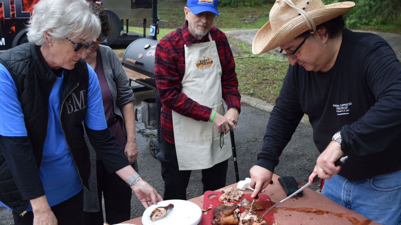 People gather around a pit master as he cuts into Kosher BBQ. (The Texas Kosher BBQ Championship)