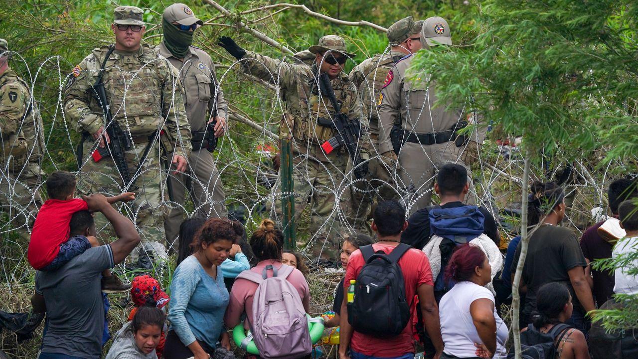 A Texas National Guard member speaks to migrants who swam to the U.S. side of the bank of the Rio Grande river (Fernando Llano/AP)