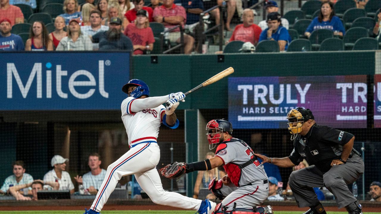 Texas Rangers' Adolis Garcia, left, follows through on a walkoff home run off Washington Nationals relief pitcher Kyle Finnegan as catcher Keibert Ruiz, center, and home plate umpire Laz Diaz, right, look on during the ninth inning of a baseball game Saturday, June 25, 2022, in Arlington, Texas. (AP Photo/Jeffrey McWhorter)