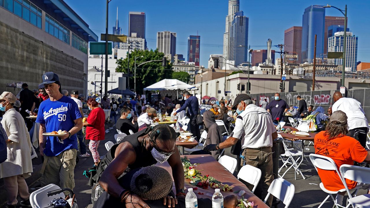 People partake in a free Thanksgiving meal provided by the Union Rescue Mission as the Los Angeles Skid Row district annual feast hosts thousands of homeless and others in need in downtown Los Angeles on Thursday, Nov. 25, 2021. (AP Photo/Damian Dovarganes)