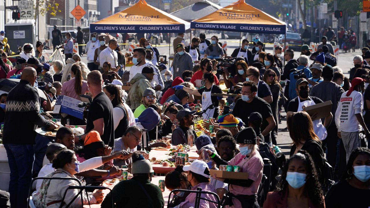 People partake in a free Thanksgiving meal provided by the Union Rescue Mission as the Los Angeles Skid Row district annual feast hosts thousands of homeless and others in need in downtown LA on Thursday. (AP Photo/Damian Dovarganes)