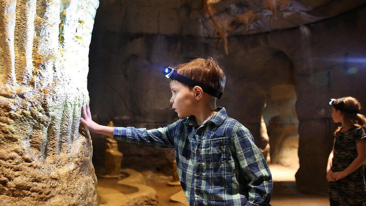 A child touches a rock surface inside "The Cave," a decades-old interactive exhibit at the Cincinnati Museum Center. (Photo courtesy of Cincinnati Museum Center)