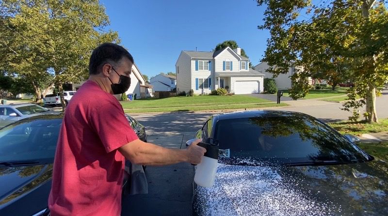 man spraying foam on his car