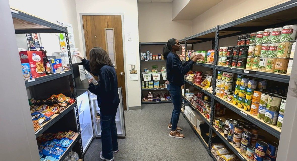 Lynn Frausto, left, and Katrina Prickett are enrolled at Davidson-Davie Community College. The volunteers are stocking the school's food pantry. (Spectrum News 1/Jennifer Roberts)