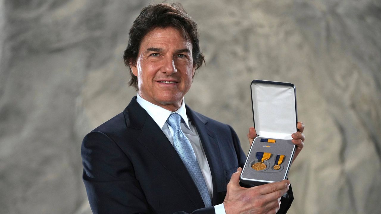 Tom Cruise poses with the Navy Distinguished Public Service Award received from U.S. Secretary of the Navy Carlos Del Toro at the Longcross South Studios in Runnymede, Surrey, England, Tuesday, Dec. 17, 2024. (AP Photo/Kin Cheung)