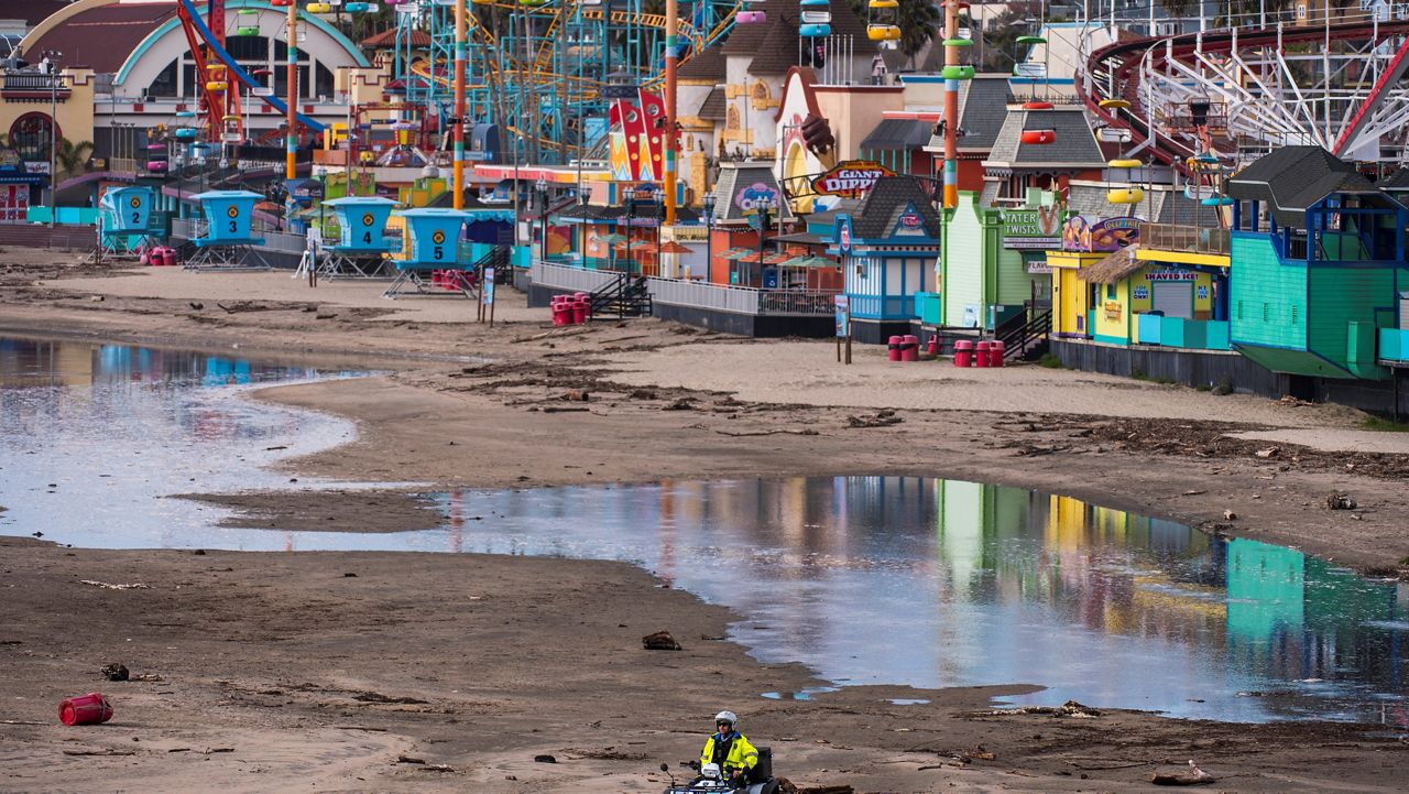 A police officer patrols main beach as waters recede in front of the Santa Cruz Beach Boardwalk in Santa Cruz, Calif., Saturday, Jan. 15, 2022. (AP Photo/Nic Coury)