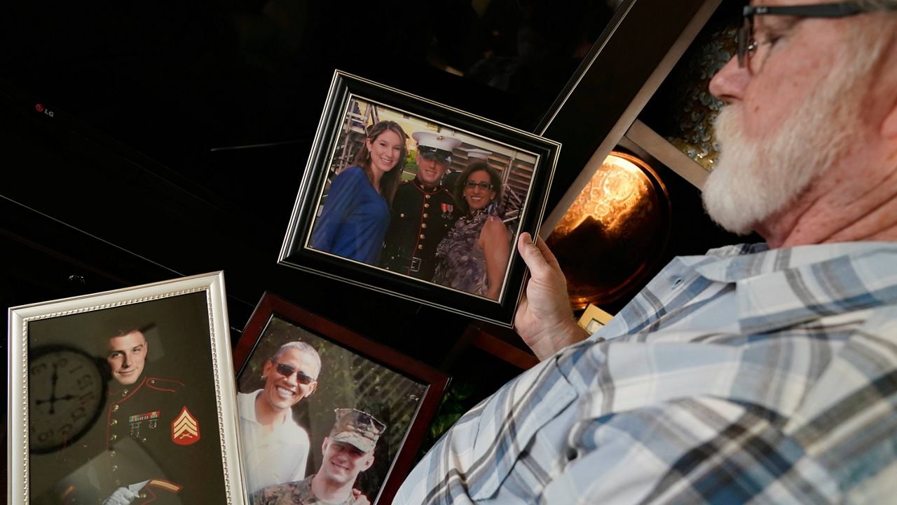 Joey Reed holds photos of his son, Marine veteran Trevor Reed, at his home in Fort Worth, Texas, on Feb. 15. (AP Photo/LM Otero, File)