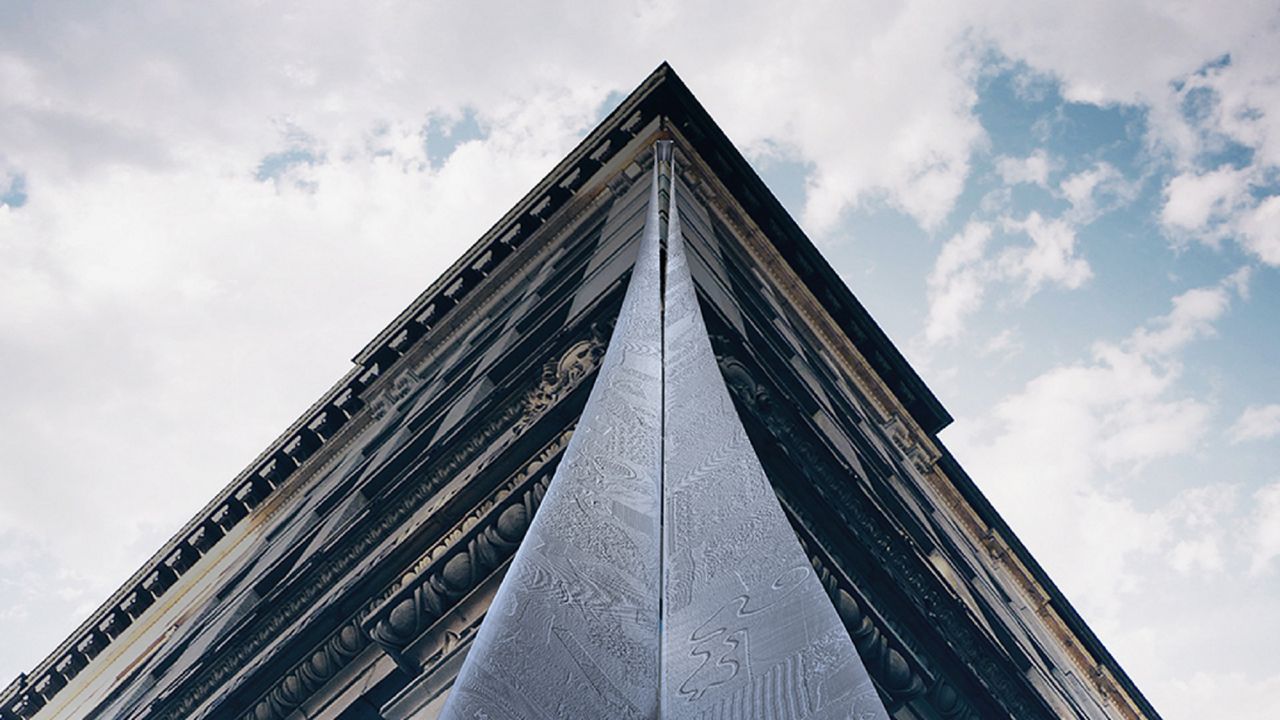 The Triangle Factory Fire Memorial design features a 300-foot-long textured stainless-steel ribbon etched by Akron Metal Etching that will begin at the corner of the 9th floor, and descend to the street. 