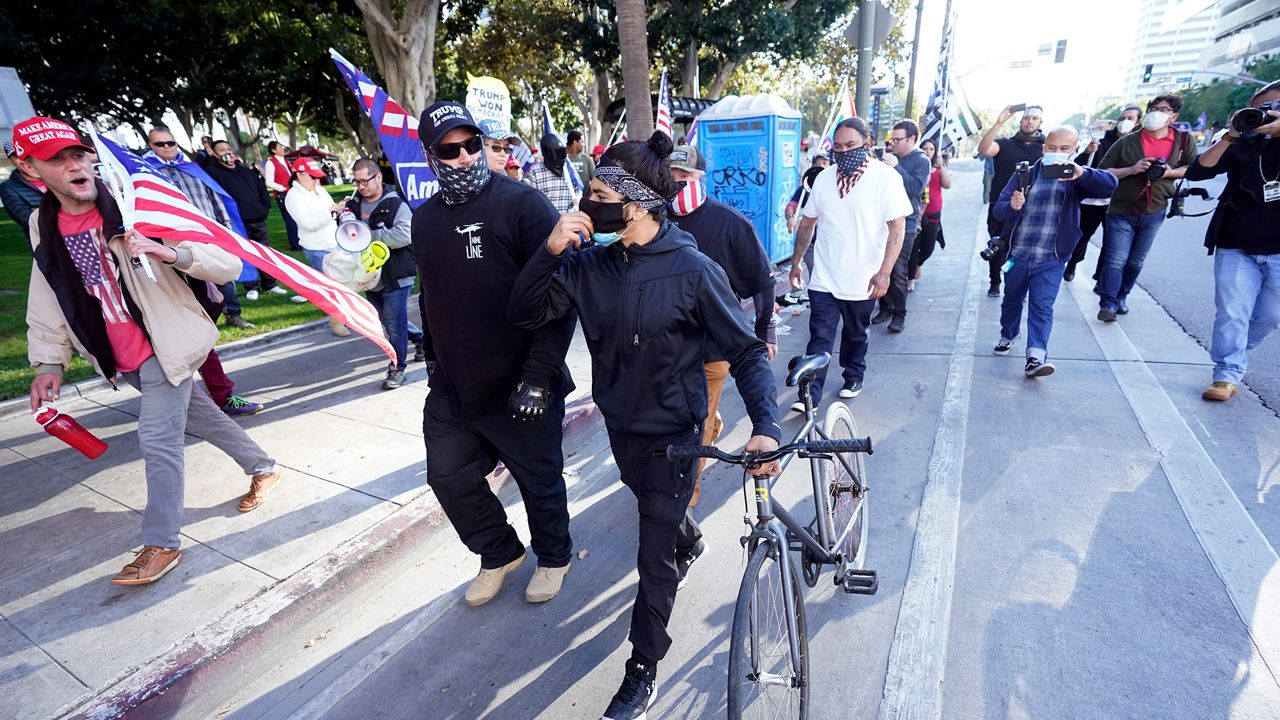 A counter demonstrator, center, is chased by Donald Trump supporters outside of City Hall Wednesday, Jan. 6, 2021, in Los Angeles. Demonstrators, supporting President Donald Trump, are gathering in various parts of Southern California as Congress debates to affirm President-elect Joe Biden's electoral victory. (AP Photo/Marcio Jose Sanchez)