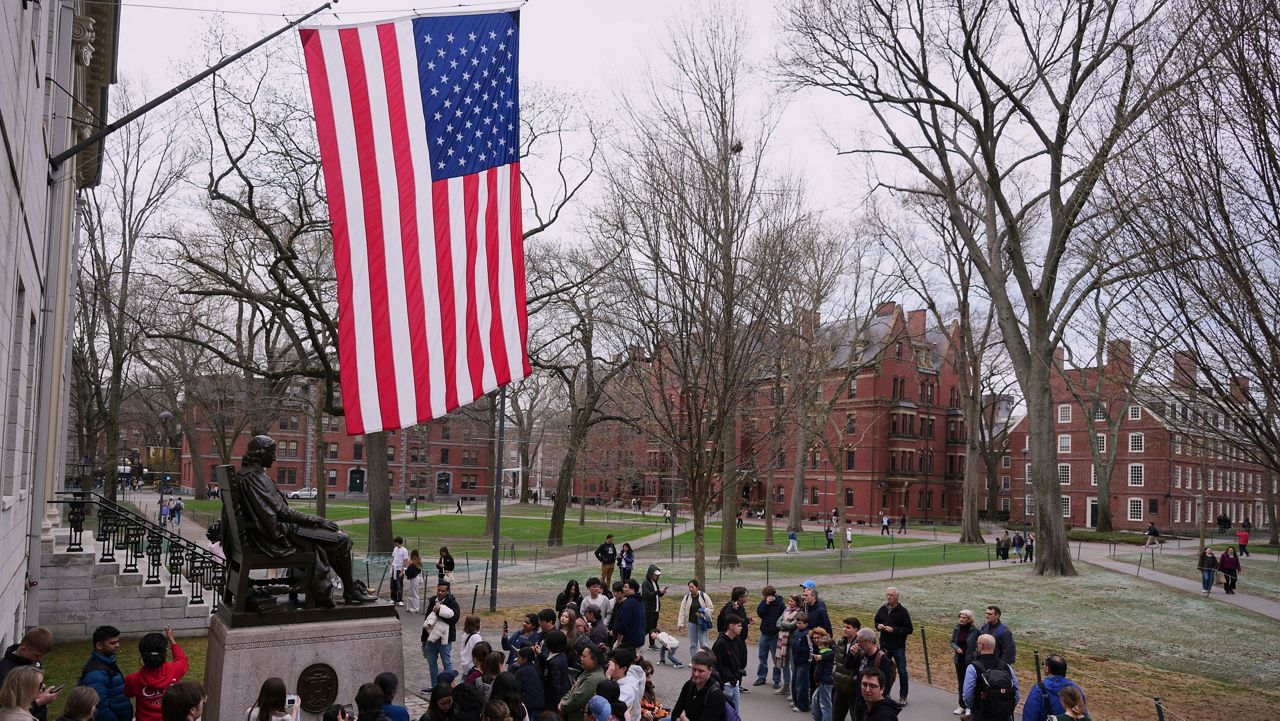 Visitors stop at the statue of John Harvard in Harvard Yard at Harvard University, Tuesday, April 15, 2025, in Cambridge, Mass. (AP Photo/Charles Krupa)