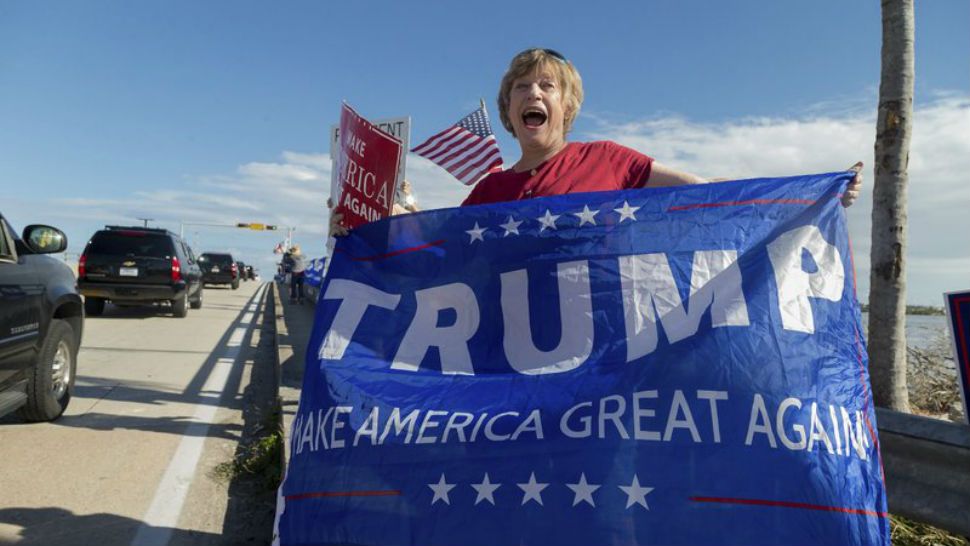 Mary Jude Smith cheers for President Donald Trump as his motorcade passes by on Southern Blvd. enroute to his Mar-a-Lago estate from Trump International Golf Club, Thursday, Dec. 28, 2017, in West Palm Beach, Fla. (Greg Lovett/Palm Beach Post via AP)