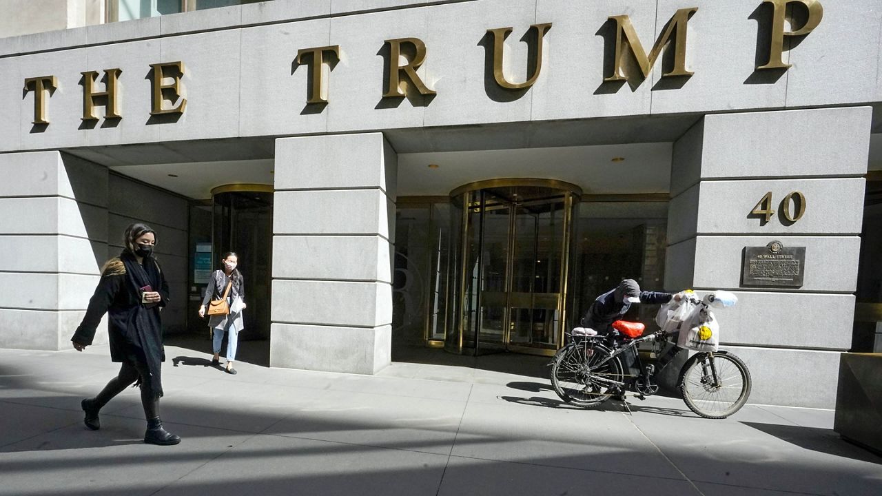 Pedestrians and a food delivery man are seen outside the Trump building on Wall Street in New York's Financial District on March 23, 2021. (AP Photo/Mary Altaffer, File )