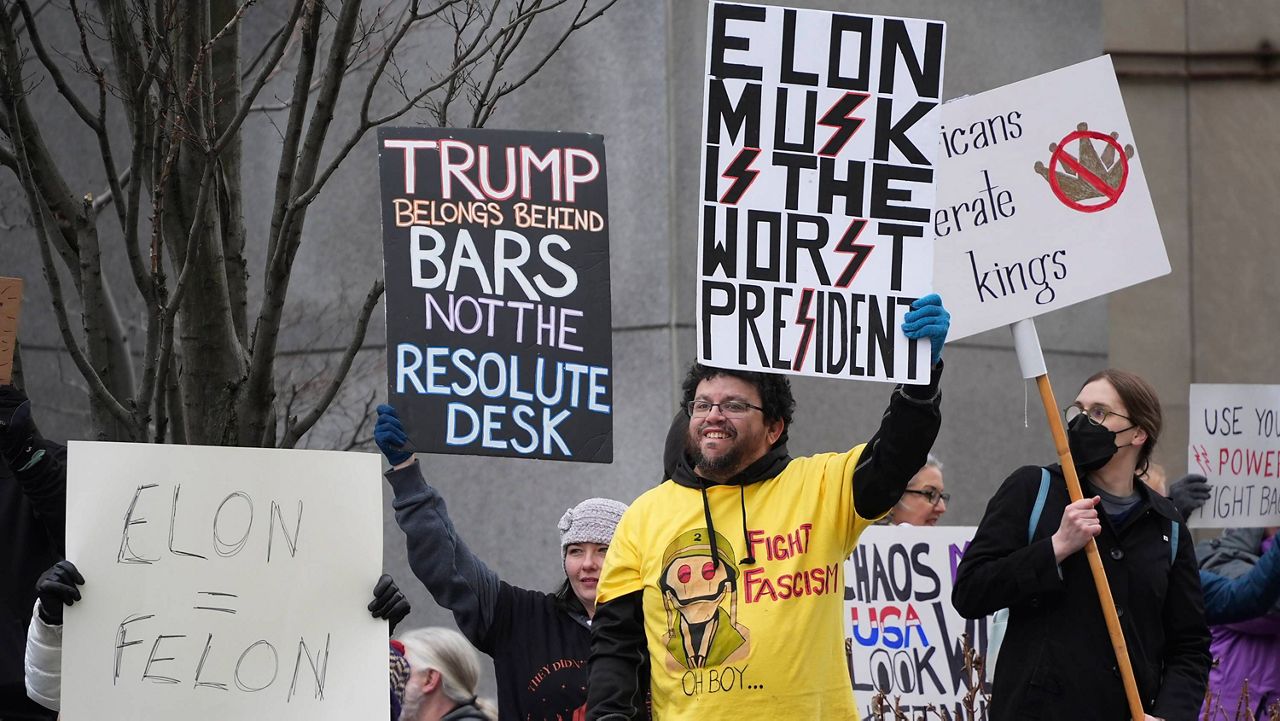 People hold up signs outside the federal courthouse before a protest in Pittsburgh on Wednesday, Feb. 5, 2025. (AP Photo/Gene J. Puskar)