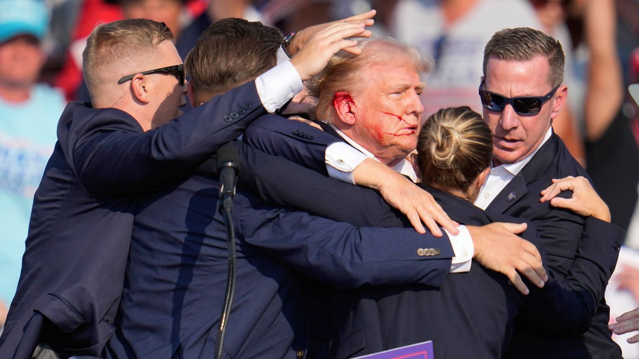 Republican presidential candidate former President Donald Trump is surrounded by U.S. Secret Service agents as he is helped off the stage at a campaign rally in Butler, Pa., Saturday, July 13, 2024. (AP Photo/Gene J. Puskar)