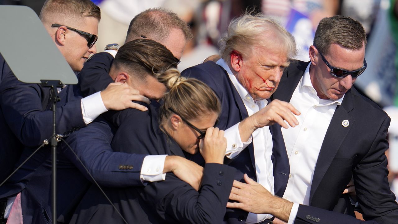 Republican presidential candidate former President Donald Trump is helped off the stage by U.S. Secret Service agents at a campaign event in Butler, Pa., on Saturday, July 13, 2024. (AP Photo/Gene J. Puskar)