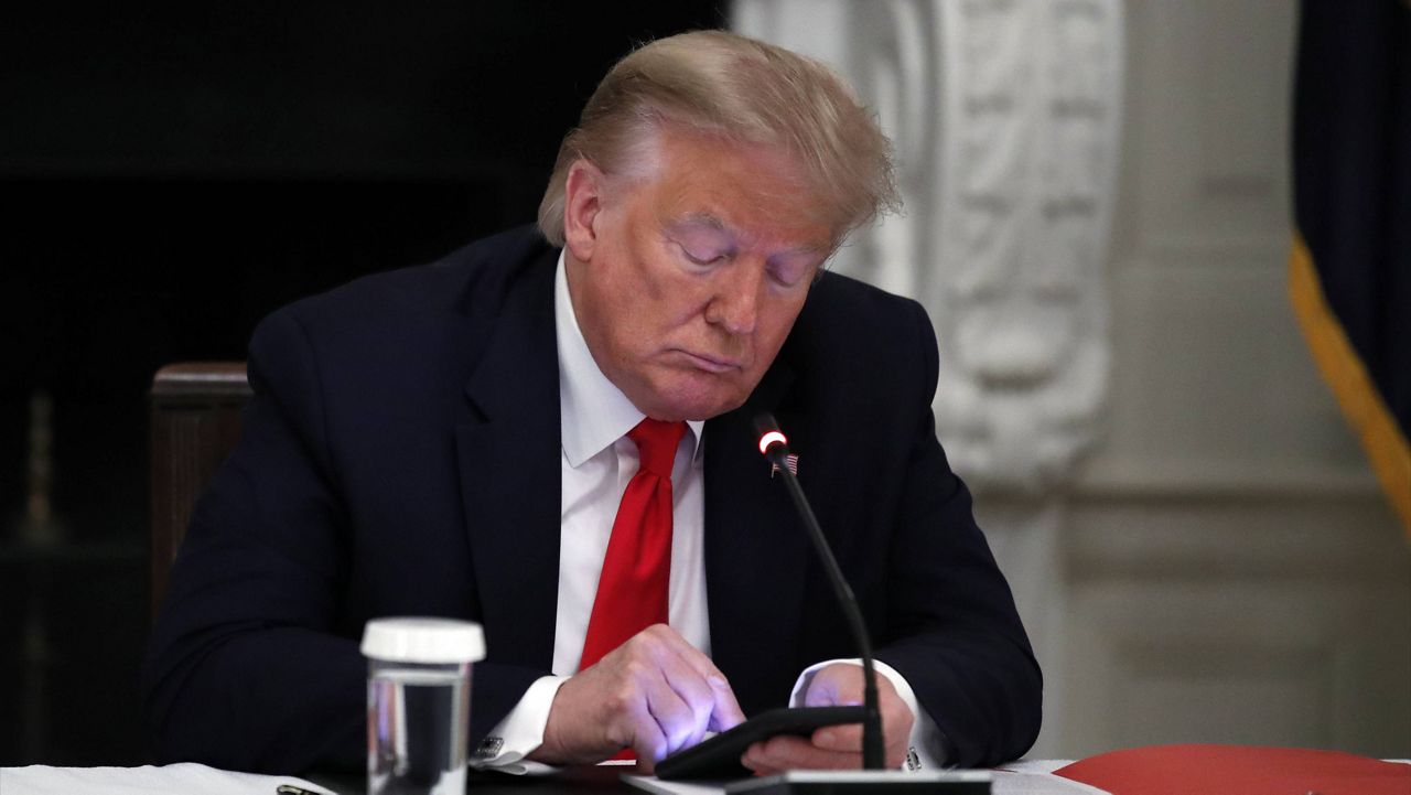 Then-President Donald Trump looks at his phone during a roundtable with governors on June 18, 2020. (AP Photo/Alex Brandon, File)