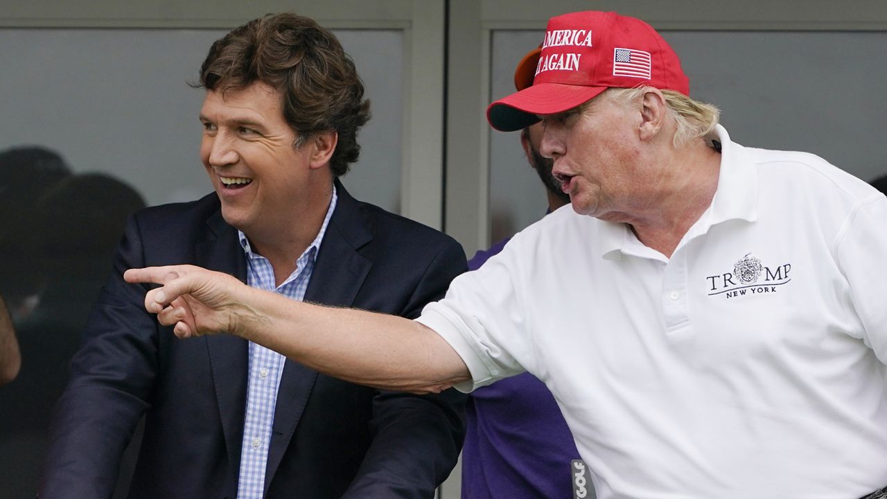 Tucker Carlson, left, and former President Donald Trump, talk while watching golfers on the 16th tee during the final round of the LIV Golf Invitational at Trump National in Bedminster, N.J., July 31, 2022. (AP Photo/Seth Wenig)