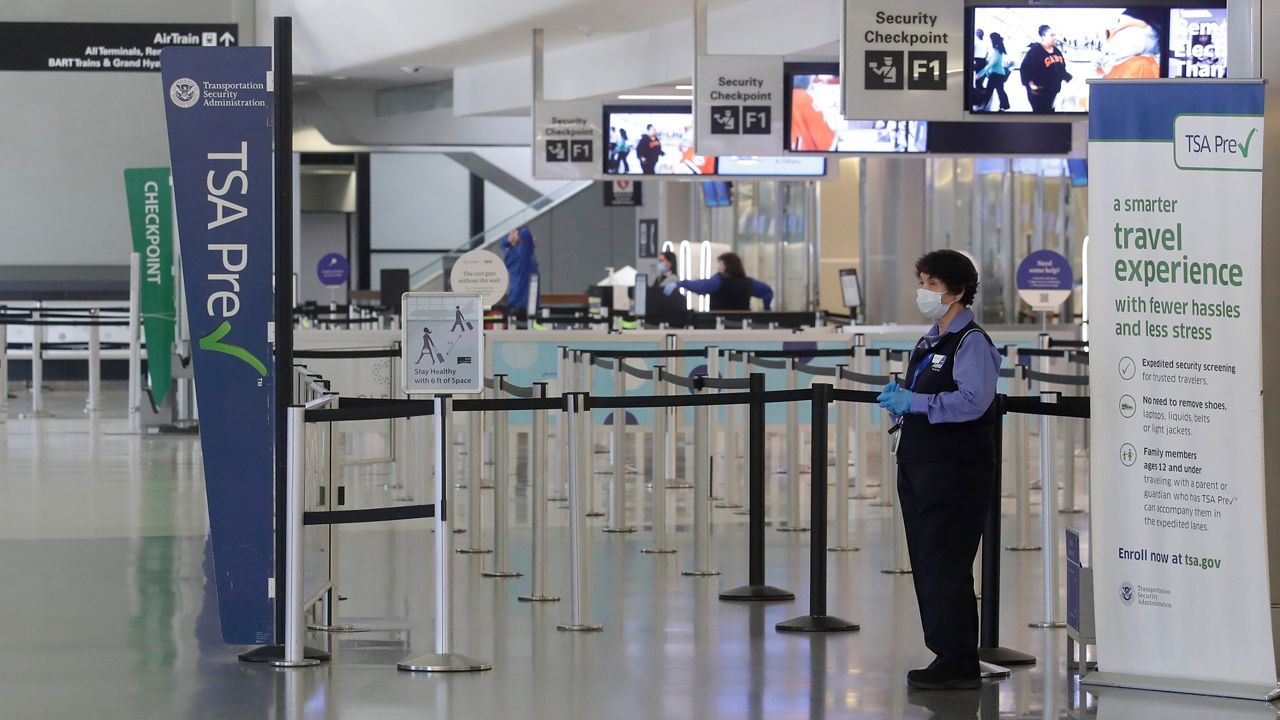 A worker wears a mask while standing near a TSA precheck entrance in a terminal at San Francisco International Airport in San Francisco, Tuesday, April 14, 2020. (Jeff Chiu/AP)