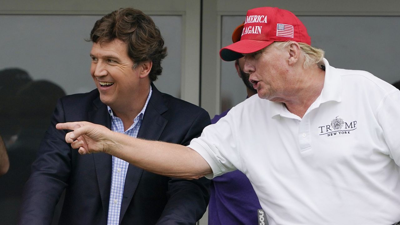 Tucker Carlson, left, and former President Donald Trump talk while watching golfers at the LIV Golf Invitational at Trump National in Bedminster, N.J., on July 31, 2022. (AP Photo/Seth Wenig, File)