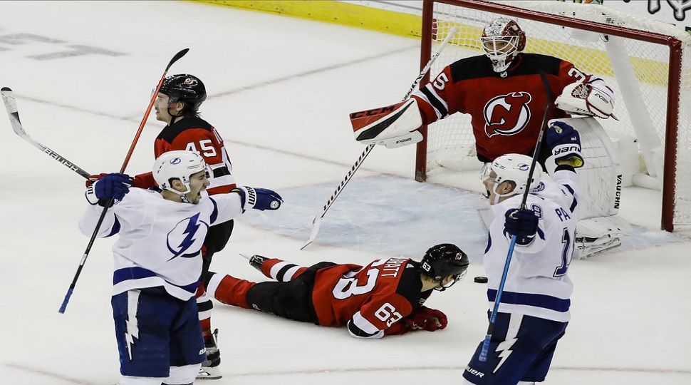 Tampa Bay Lightning’s Tyler Johnson, left, celebrates with Ondrej Palat, right, as New Jersey Devils’ Jesper Bratt (63) and goaltender Cory Schneider react after Johnson scored during overtime in an NHL hockey game Wednesday, Oct. 30, 2019, in Newark, N.J. The Lightning won 7-6. (Frank Franklin II/AP)