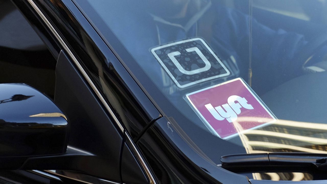 A ride-share car displays Lyft and Uber stickers on its front windshield in downtown Los Angeles. (AP Photo/Richard Vogel, File)