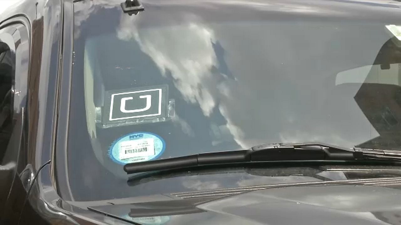 An Uber sticker is displayed in the corner of a car windshield (Spectrum News Images)