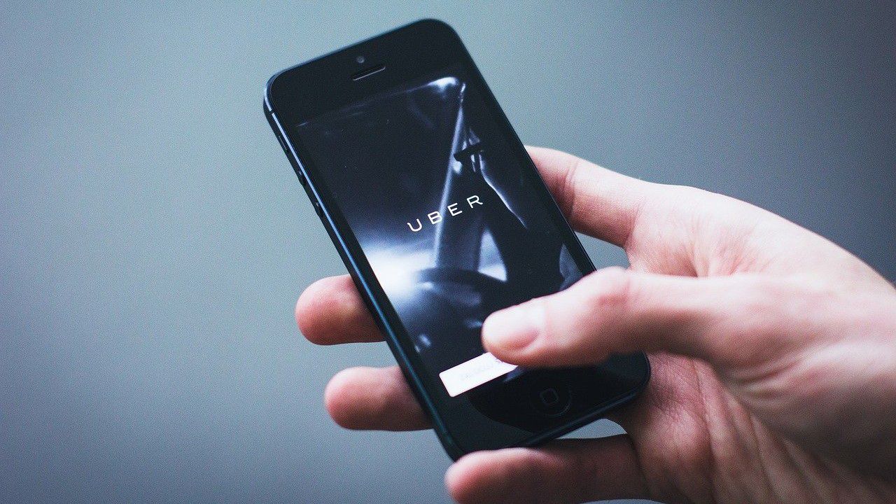 A person holds a phone with the Uber app open (Pixabay)