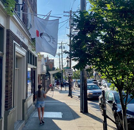 A student walks in the business district near the University of Cincinnati campus. A business flies a UC flag. (Casey Weldon | Spectrum News 1)