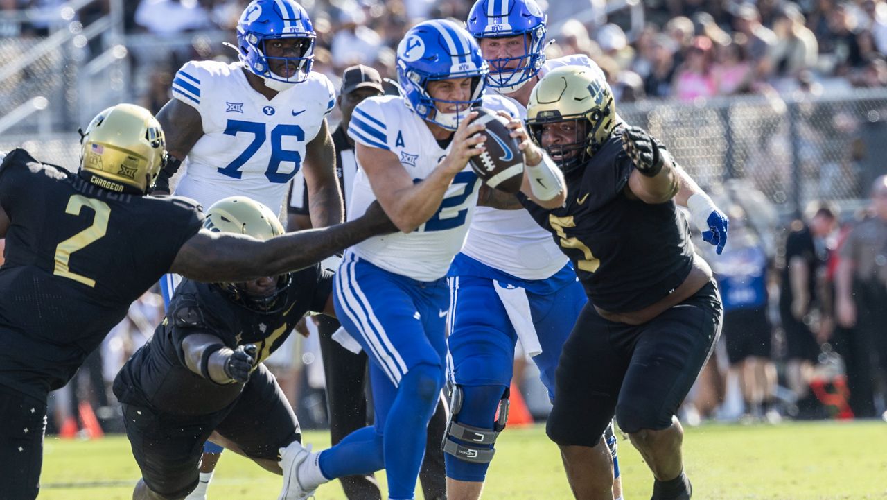 BYU quarterback Jake Retzlaff, Center, is sacked by Central Florida's defense during the first half of an NCAA college football game, Saturday, Oct. 26, 2024, in Orlando, Fla. (AP Photo/Kevin Kolczynski)