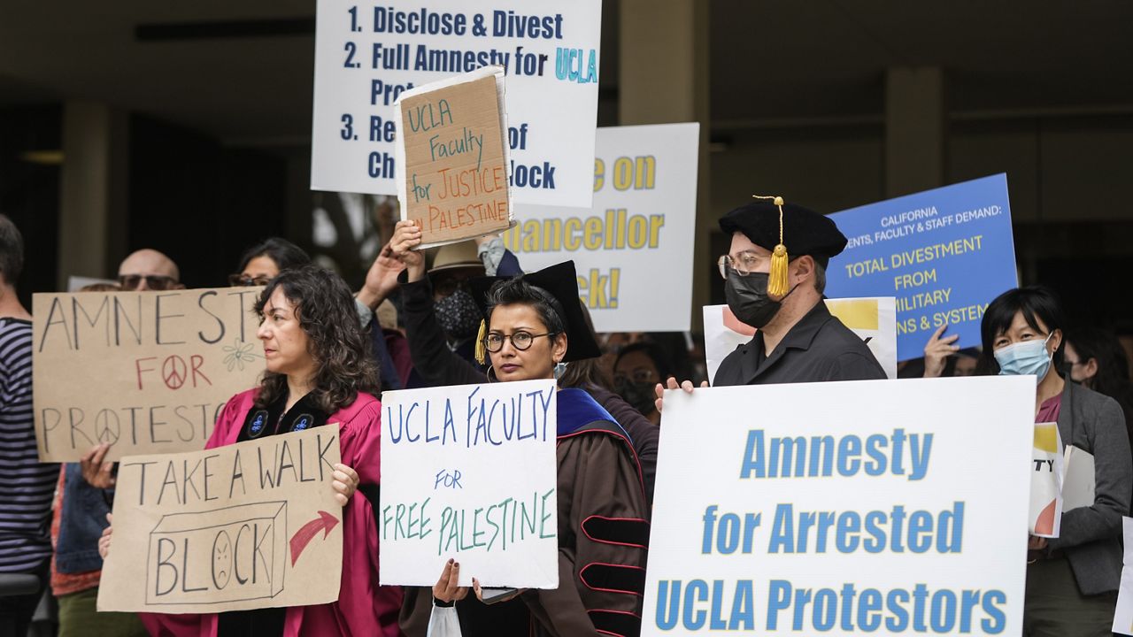 UCLA faculty and staff members hold signs during a news conference at UCLA in Los Angeles, Thursday, May 9, 2024. Weekend commencement ceremonies at some U.S. universities went off with few interruptions despite the national wave of protests over the Israel-Hamas war. (AP Photo/Jae C. Hong)