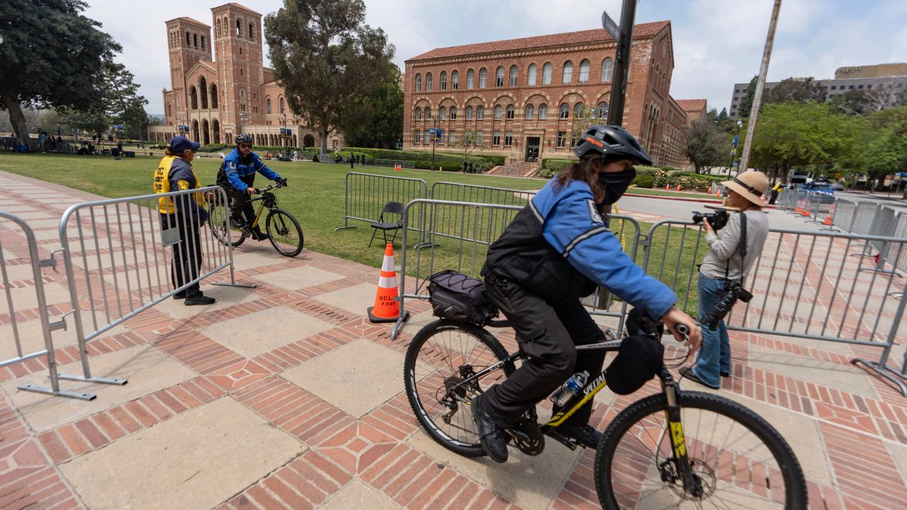 Security ride their bicycles around steel barriers blocking public access around the Royce Hall area of the UCLA campus on Friday. (AP Photo/Damian Dovarganes)