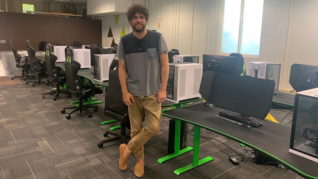 Sky Kauweloa, who heads up the University of Hawaii's esports program, stood next to the school's new gaming computers in the UH Esports Arena.