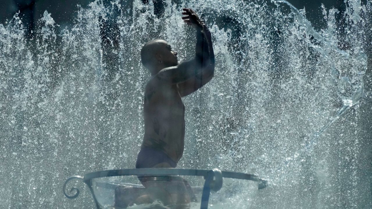 A man sits in a glass bowl Tuesday in a fountain on the Southbank in London. (AP Photo/Frank Augstein)