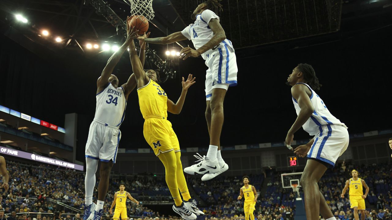 Michigan Wolverines' Tarris Reed Jr. (32) goes for the basket as Kentucky Wildcats' Oscar Tshiebwe (34) and Kentucky Wildcats' Daimion Collins (4) defend during an NCAA basketball game between Michigan Wolverines and Kentucky Wildcats at the O2 Arena, in London, Sunday, Dec.4, 2022. (AP Photo/Ian Walton)