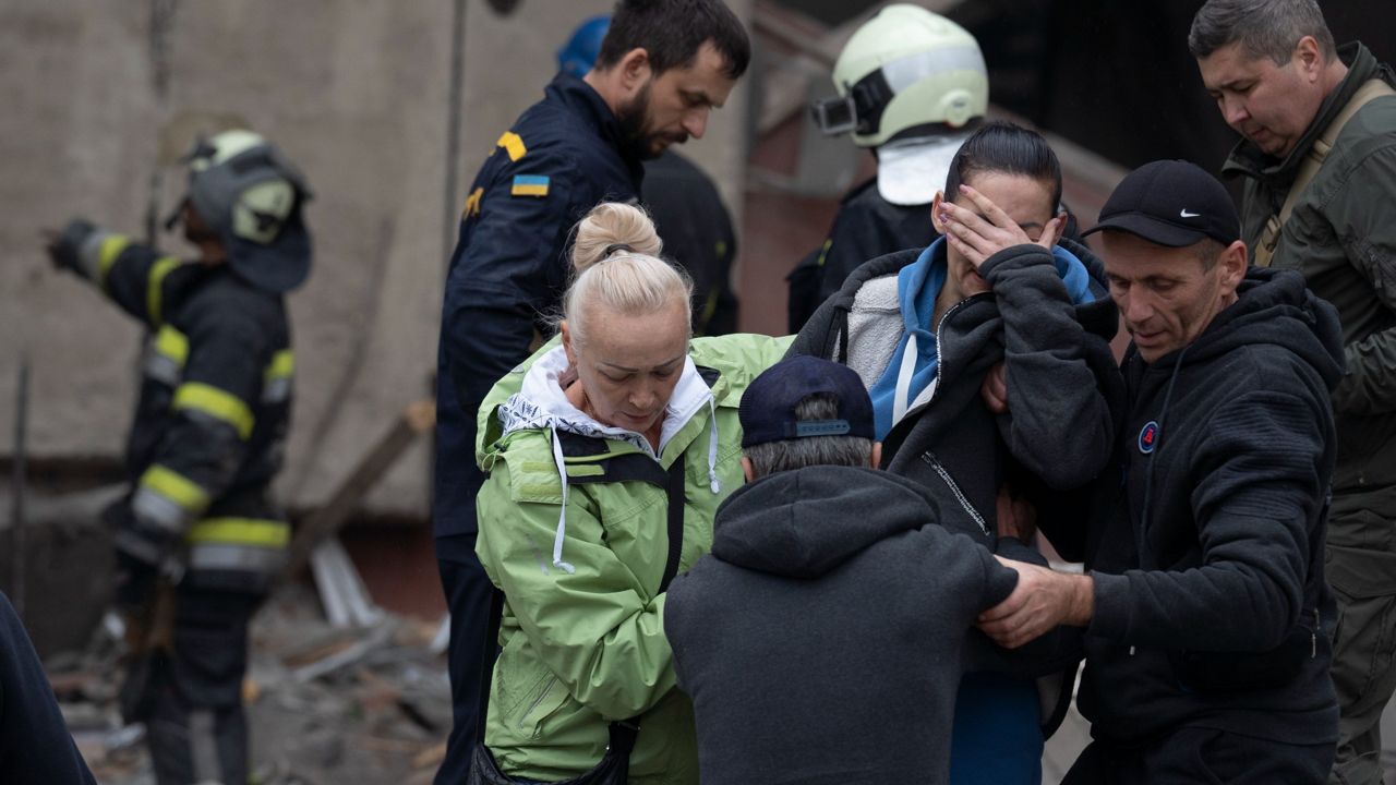 Relatives and friends comfort a woman Wednesday after Ukrainian rescue workers found a body of a person under the debris following a Russian attack that heavily damaged a school in Mykolaivka, Ukraine. (AP Photo/Leo Correa)