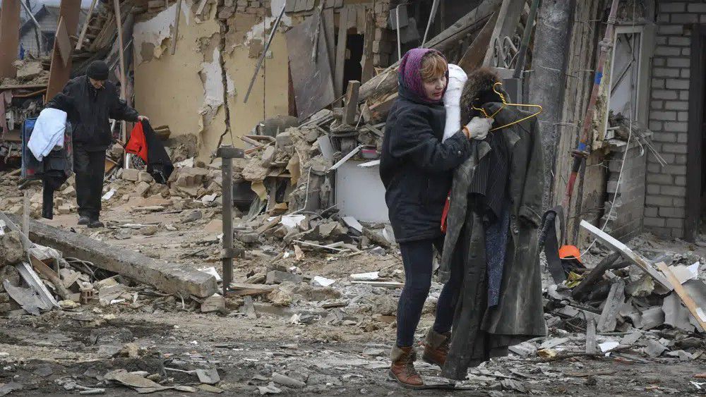 Residents carry their belongings as they leave their home ruined in the Saturday Russian rocket attack in Zaporizhzhya, Ukraine, Sunday, Jan. 1, 2023. (AP Photo/Andriy Andriyenko)