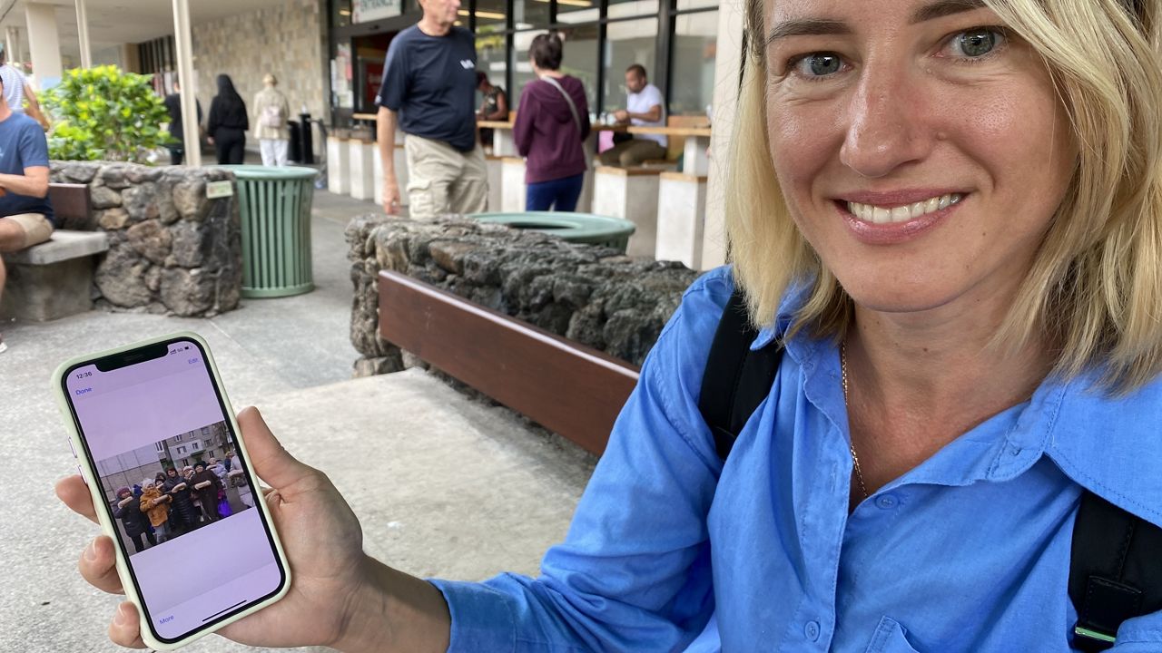 Mariia Babinska displays an image on her phone of volunteers in Ukraine with loaves of bread. (Spectrum News Hawaii/Michelle Broder Van Dyke)