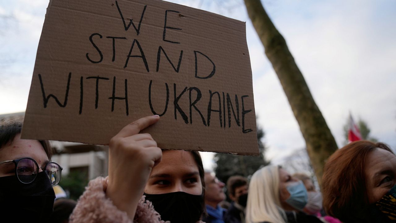 A protestor holds up a sign during a demonstration in front of the Russian embassy in Paris, France, Tuesday, Feb. 22, 2022. (AP Photo/Francois Mori)