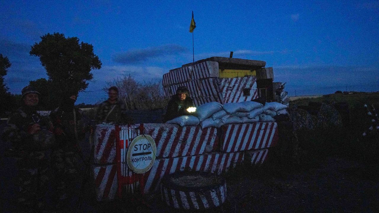 Ukrainian servicemen stand guard at a check point, during night time curfew, in Donetsk region, eastern Ukraine, Friday, July 22, 2022. (AP Photo/Nariman El-Mofty)