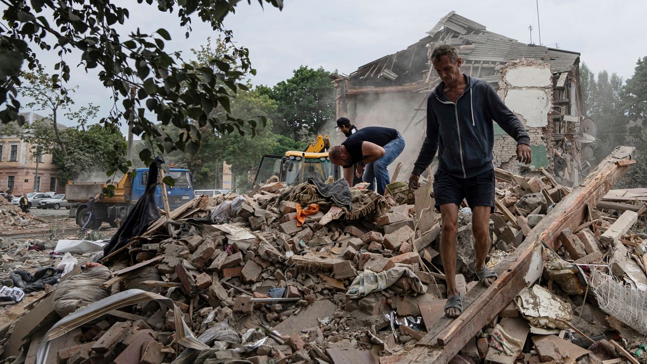 Local residents search for documents of their injured friend in the debris of a destroyed apartment house after Russian shelling in a residential area in Chuhuiv, Kharkiv region, Ukraine, Saturday, July 16, 2022. (AP Photo/Evgeniy Maloletka)