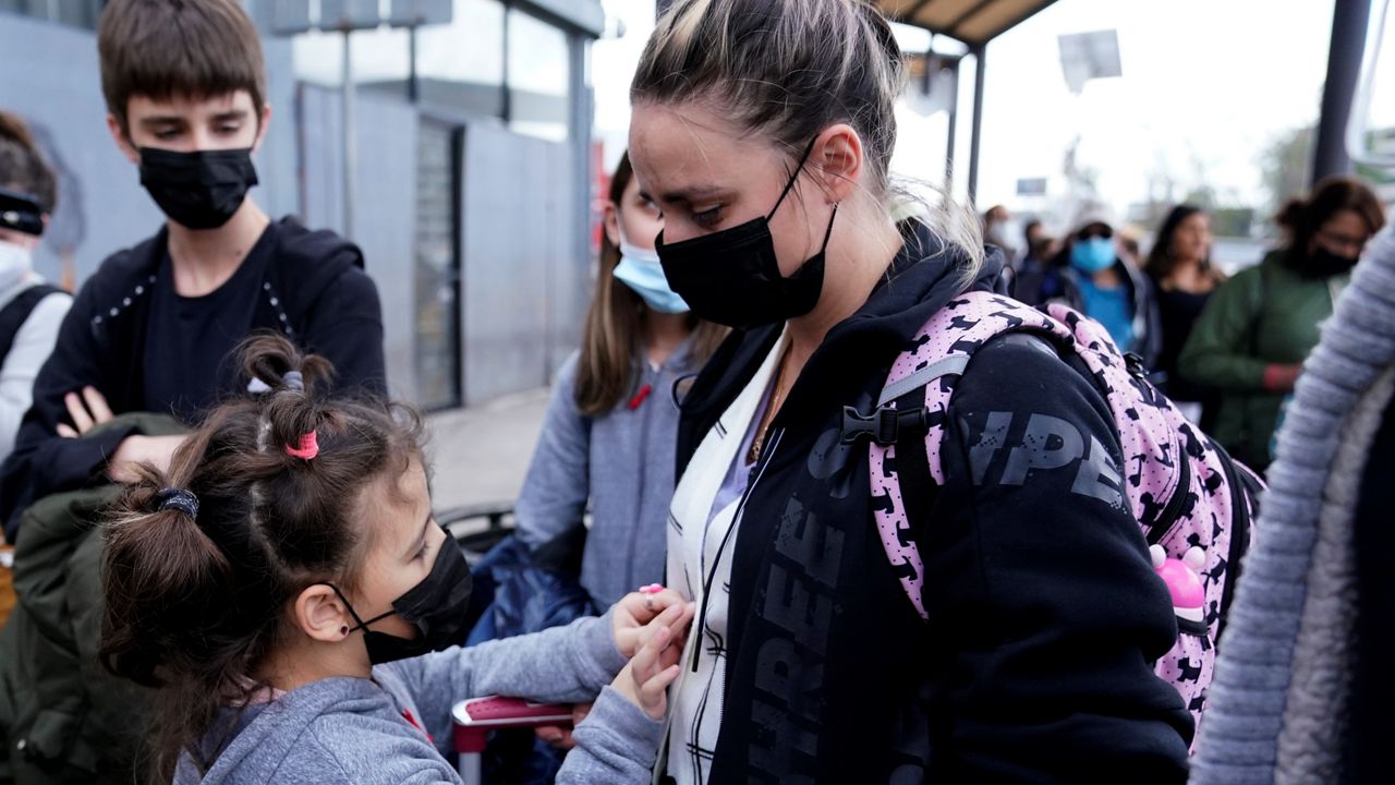 A woman from Ukraine stands with her children before crossing into the United States, Thursday, March 10, 2022, in Tijuana, Mexico. (AP Photo/Gregory Bull)