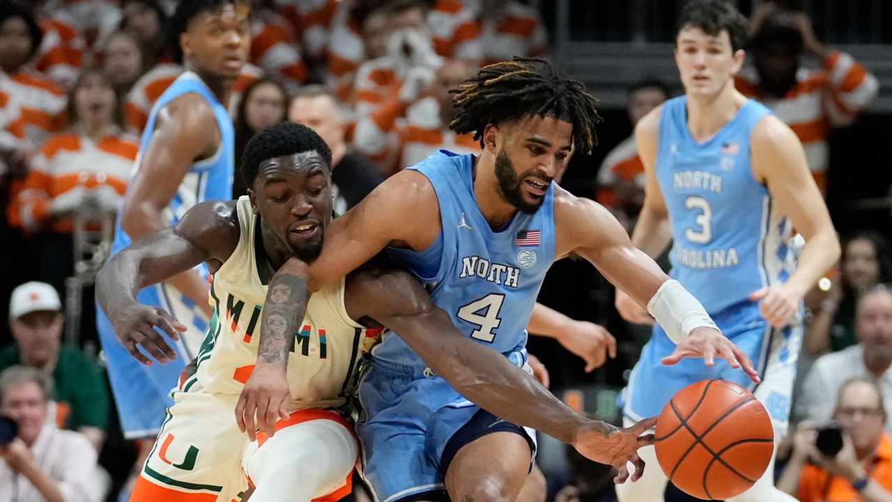 North Carolina guard RJ Davis, center right, and Miami guard Bensley Joseph battle for a ball during the second half of an NCAA college basketball game Saturday, Feb. 10, 2024, in Coral Gables, Fla. North Carolina defeated Miami 75-72. (AP Photo/Rebecca Blackwell)