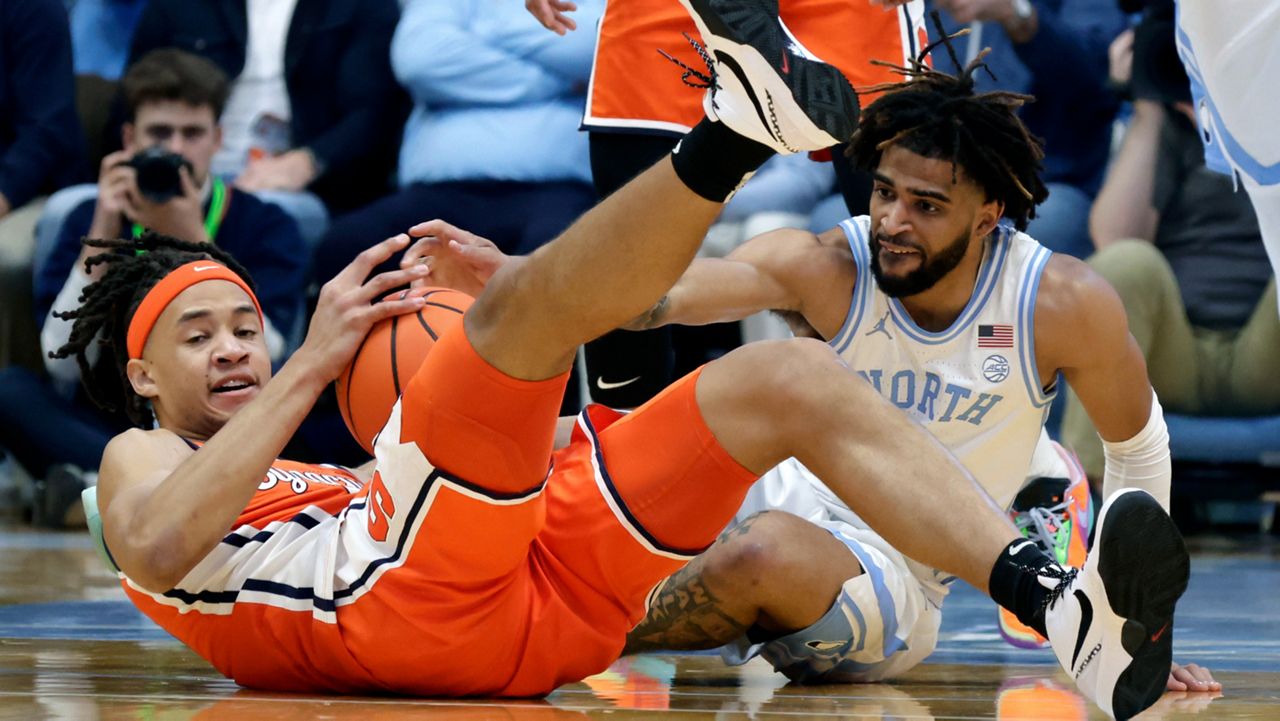 Syracuse forward Benny Williams, left, and North Carolina guard RJ Davis, right, try to get control of a loose ball during the first half of an NCAA college basketball game Saturday, Jan. 13, 2024, in Chapel Hill, N.C. (AP Photo/Chris Seward)