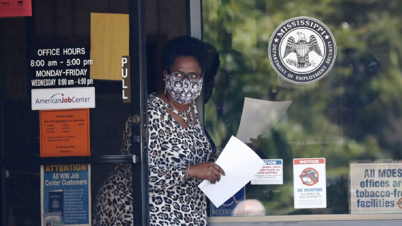 A Mississippi Department of Employment Security worker, wearing a mask to protect against coronavirus, holds an unemployment benefit application form, April 2020. (AP Photo/Rogelio V. Solis, File)