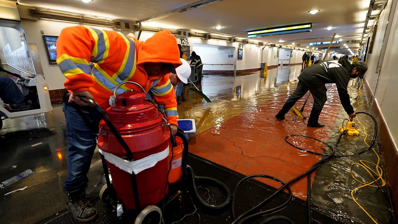 Crews work to drain rainwater flooding the Union Station's pedestrian passageway, which leads to train platforms in Los Angeles, Tuesday, Jan. 10, 2023. (AP Photo/Damian Dovarganes)