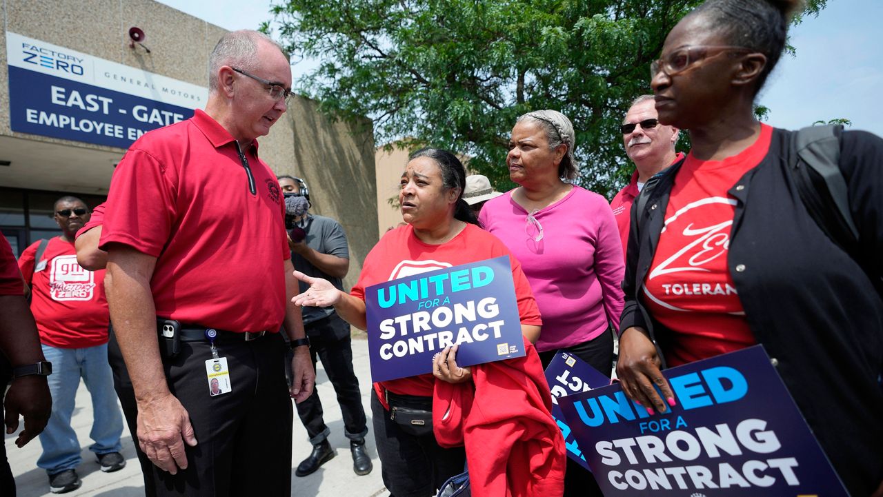 United Auto Workers President Shawn Fain, left, talks with autoworkers outside the General Motors Factory Zero plant in Hamtramck, Mich., on July 12. (AP Photo/Paul Sancya, File)