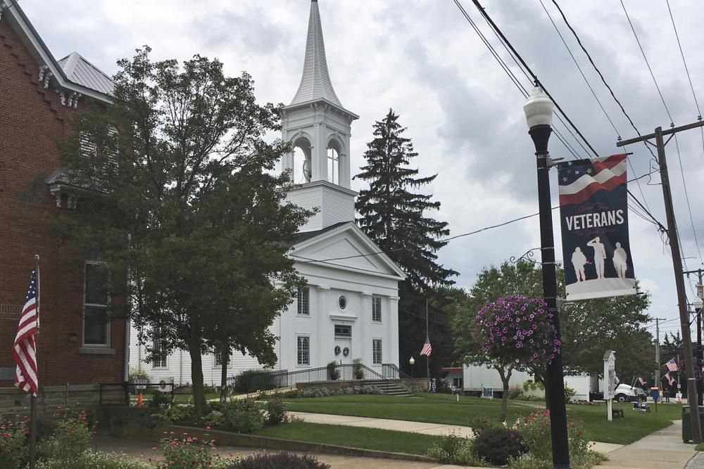 A flag rests at half-staff and a veterans banner rests outside the United Church of Christ in Berlin Heights, Ohio. Maxton Soviak, a U.S. Navy Fleet Marine Force hospital corpsman, was killed Thursday in Afghanistan. Soviak lived in Berlin Heights, Ohio. (AP Photo/John Seewer)