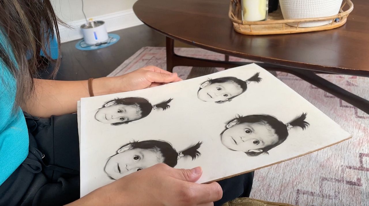 Barbara Mojica Arzat, a DACA recipient, looks at baby pictures of herself. (Spectrum News 1/Anissa Lopez) 
