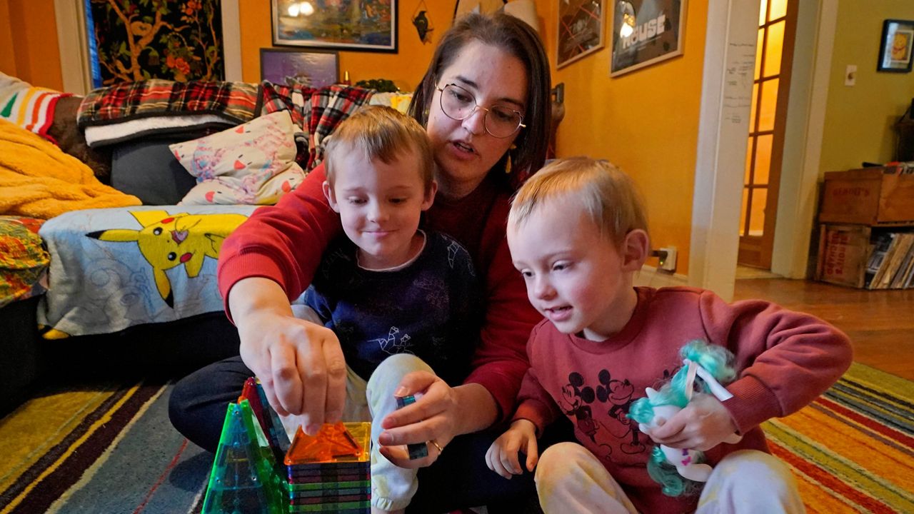 Heather Cimellaro builds a toy house Wednesday with her twins, Milo, left, and Charlie, at their home in Auburn, Maine. (AP Photo/Robert F. Bukaty)