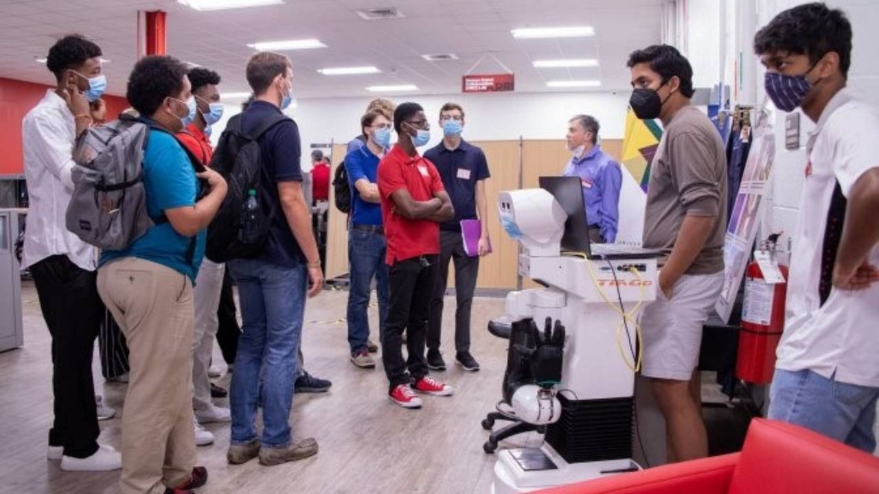 Students stand around Tiago the robot at UofL's Automation and Robotics Research Institute. (University of Louisville)